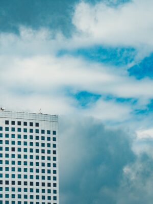 Fragment of exterior of modern skyscraper with white facade and glass windows against cloudy blue sky